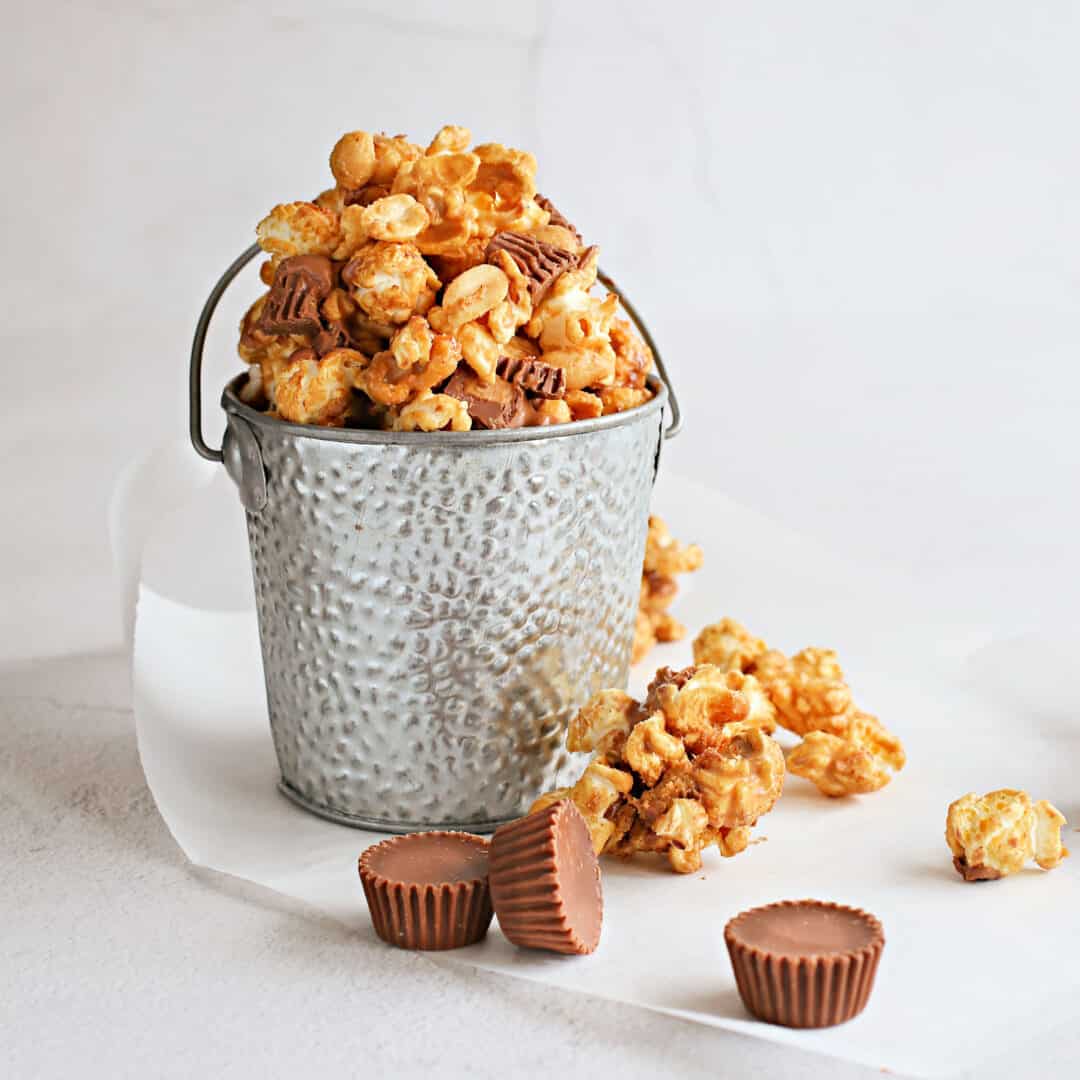 Chocolate Peanut Butter Cup Popcorn combines freshly popped corn with creamy peanut butter, melted chocolate, roasted peanuts and pieces of peanut butter cups.